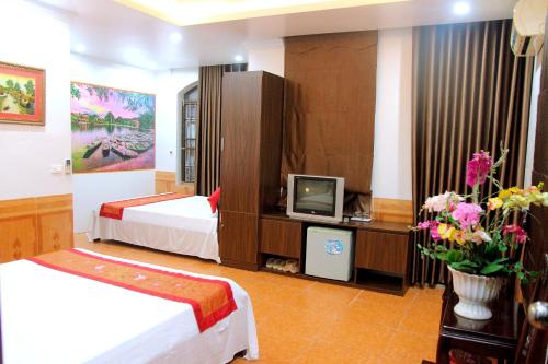 a hotel room with two beds and a tv at Xuan Hoa Hotel in Ninh Binh