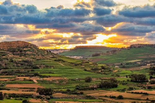 a view of a green valley at sunset at Ghajn Damma in Xagħra