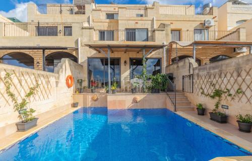 a large blue swimming pool in front of a building at Ghajn Damma in Xagħra