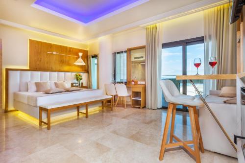 Porto Marine Hotel في بلاتامون: غرفة نوم مع سرير وطاولة مع كؤوس للنبيذ