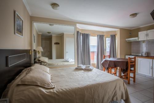 a bedroom with a large bed with a table and a kitchen at Antu Mahuida Apartments in San Carlos de Bariloche