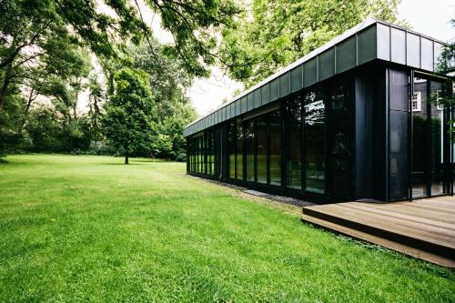 a black building in a park with a grass field at Parkhotel FRITZ am Brunnen in Schwelm