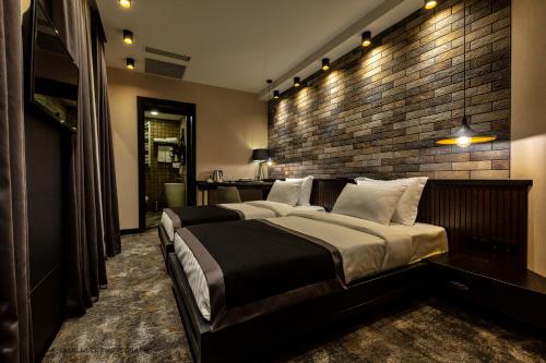 a bedroom with a large bed with a brick wall at Hotel Adamo in Tbilisi City