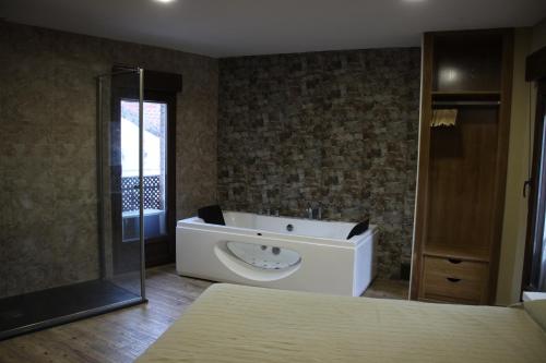 y baño con bañera y ducha acristalada. en Casa Rural Casa de Chocolate, en Cuevas del Valle