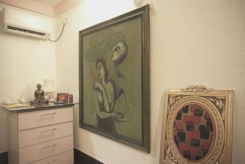 a painting of two women on a wall next to a dresser at Reena's Lodge in Kolkata