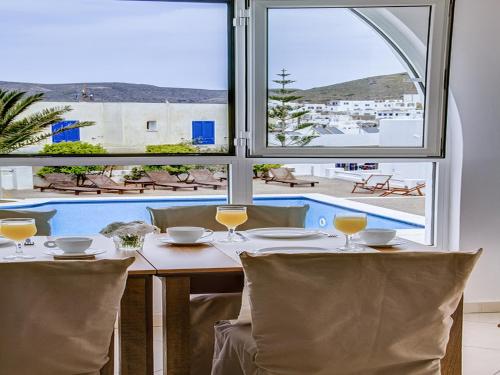 a table with wine glasses and a view of a pool at Avanti in Ios Chora