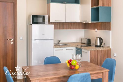 a kitchen with a table with a bowl of fruit on it at Cascadas Family Resort in Sunny Beach