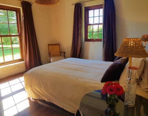 a bedroom with a bed and a table with flowers on it at Pear Tree Cottage-Underberg in Underberg