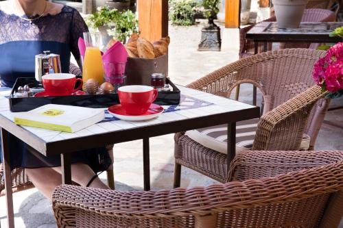 a woman sitting at a table with two red cups at Hotel et Spa Le Lion d'Or in Pont-lʼÉvêque