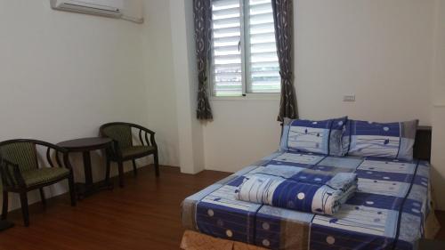 a bedroom with a bed and two chairs and a window at A-Ma Homestay in Fengli