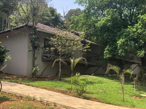 a house with a yard with trees and a driveway at Abad Brookside Wayanad in Vythiri