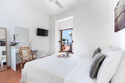 a white bedroom with a white bed and a desk at Il Cefalo Hotel & Restaurant in Castellabate