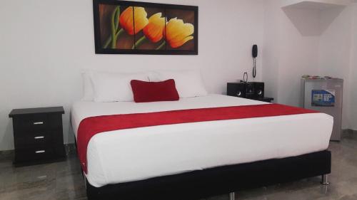 um quarto com uma cama com uma almofada vermelha em Hotel Cafe Plaza em Tuluá