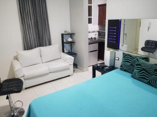 a living room with a white couch and a tv at Alegria Hostal in Santiago de los Caballeros