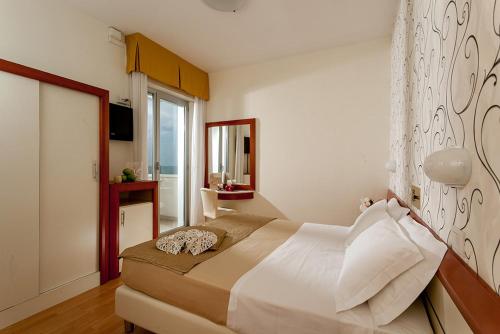 una camera con letto, finestra e specchio di Hotel Aristeo a Rimini