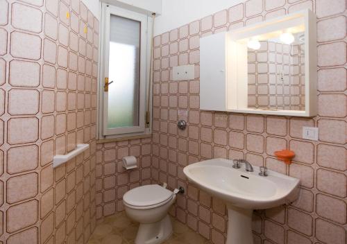 a bathroom with a sink and a toilet and a mirror at Olimpia in Bibione