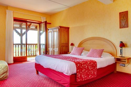 a bedroom with a large bed and a large window at Hotel Restaurant Faller Emmebuckel in Itterswiller