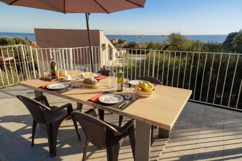 een houten tafel met stoelen en een parasol op een patio bij Casa Selvaggio Blu in Santa Maria Navarrese