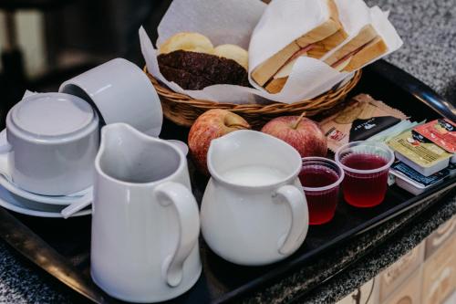 a tray with cups and a basket of bread and apples at Hotel Positano in Taguatinga