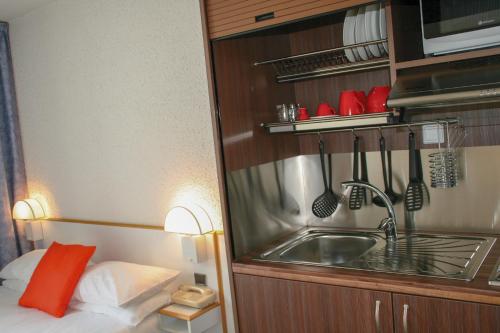 a kitchen with a sink and a microwave at Hôtel des Thermes Les Dômes in Vichy
