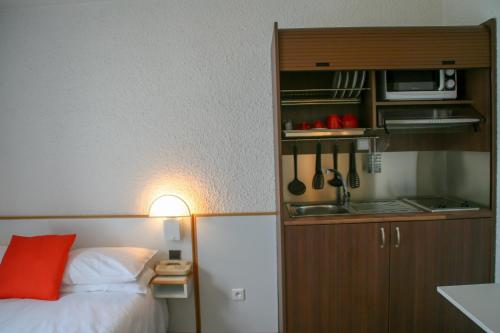 1 dormitorio con 1 cama y cocina con fregadero en Hôtel des Thermes Les Dômes, en Vichy