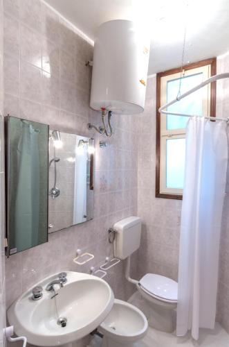 a bathroom with a sink and a toilet and a mirror at Tivoli in Bibione