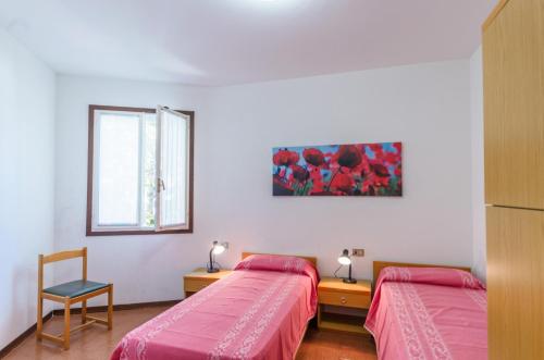 a bedroom with two beds and a window and a chair at Tivoli in Bibione