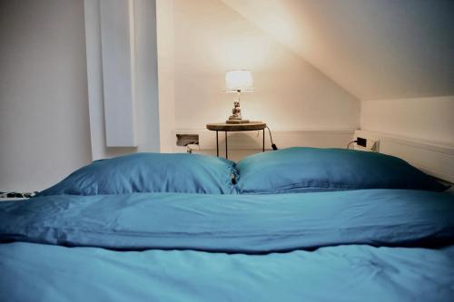 a bed with blue sheets and a lamp on a table at CityLife Residence in Bratislava