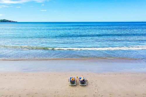 two people sitting in beach chairs on the beach at Margaritaville Beach Resort Playa Flamingo in Playa Flamingo