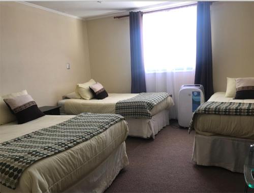 a hotel room with three beds and a window at Hotel Barba Lá in Combarbalá