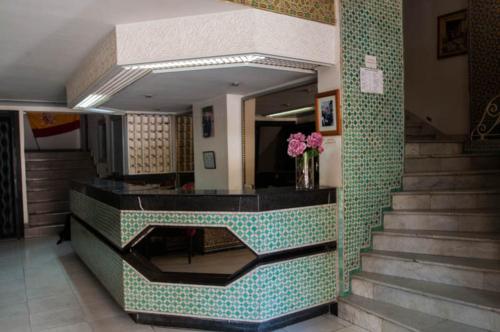 a lobby with a staircase with a vase of flowers at Hotel De La Paix in Fès