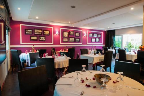 a dining room with tables and chairs and pink walls at Hotel De La Paix in Fès