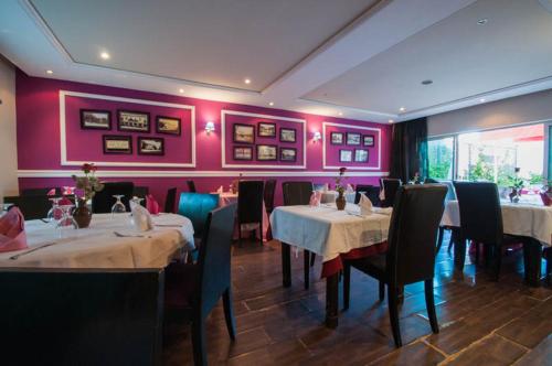 a dining room with tables and chairs and pink walls at Hotel De La Paix in Fès