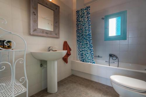 een badkamer met een wastafel, een toilet en een bad bij Villa Zefyros in Pachaina