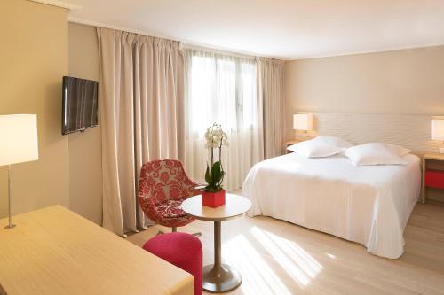 a hotel room with a bed and a table and a chair at Hôtel & SPA Oceania L'Univers Tours in Tours