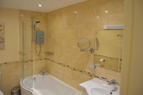 a bathroom with a tub and a sink and a mirror at Ness View Apartment in Inverness