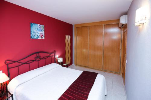 ラ・ピネーダにあるAQUAMARINA E HomeStay by Turismarの赤いベッドルーム(ベッド1台、木製キャビネット付)