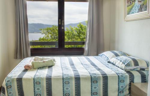 - une chambre avec un lit et une fenêtre avec vue dans l'établissement Casa em CondomÍnio Fechado com Vista para Lagoa, à Garopaba