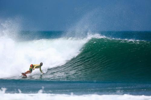 a man riding a wave on a surfboard in the ocean at Hostal Los Chamos in San Juan del Sur