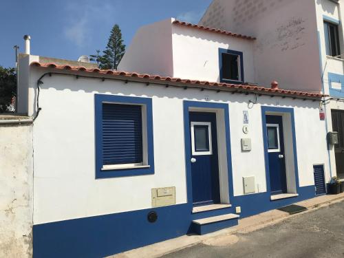 a white and blue house with blue doors at Casa Sto. António in Zambujeira do Mar