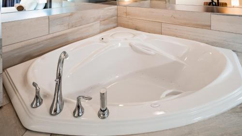 a white bath tub with two faucets in a bathroom at Best Western Plus Country Meadows Inn in Aldergrove