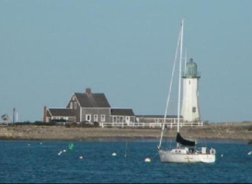 a sailboat in the water in front of a lighthouse at The Inn at Scituate Harbor in Scituate