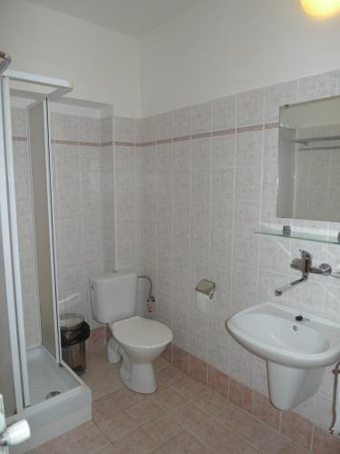 a bathroom with a toilet, sink and tub at Hotel U Černého orla in Telč
