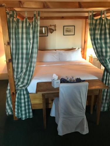 1 dormitorio con 1 cama y 1 mesa con cortinas en The Red Lion Inn, en Cohasset