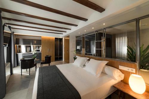 1 dormitorio con 1 cama blanca grande y escritorio en Vinatea Suites, en Morella