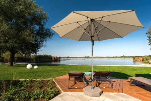 a patio with two chairs and a table with an umbrella at Donautica Hotel & Restaurant in Fadd-Dombori