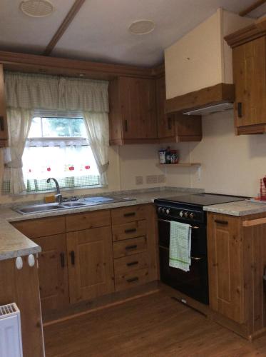 a kitchen with wooden cabinets and a black stove top oven at Tarka holiday park, 5A in Barnstaple