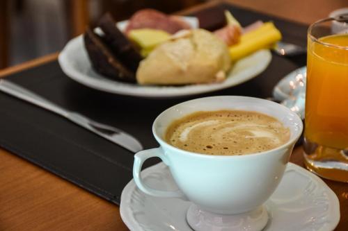 a cup of coffee on a table with a plate of food at Micheline Hotel Tricot - ao lado da Rua Coberta in Gramado