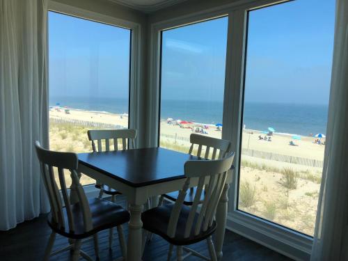 a table and chairs in a room with a view of the beach at Surf Club Oceanfront Hotel in Dewey Beach