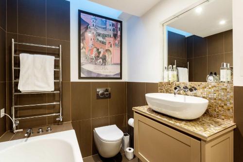 ein Badezimmer mit einem Waschbecken, einem WC und einem Spiegel in der Unterkunft Veeve - Southside Charm in London